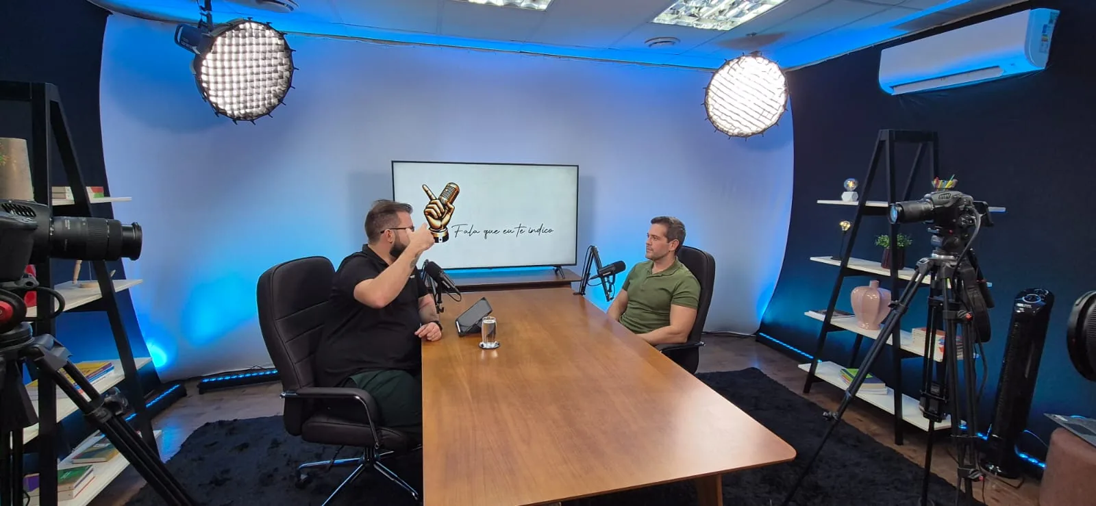Host e convidado conversando durante gravação em set azul