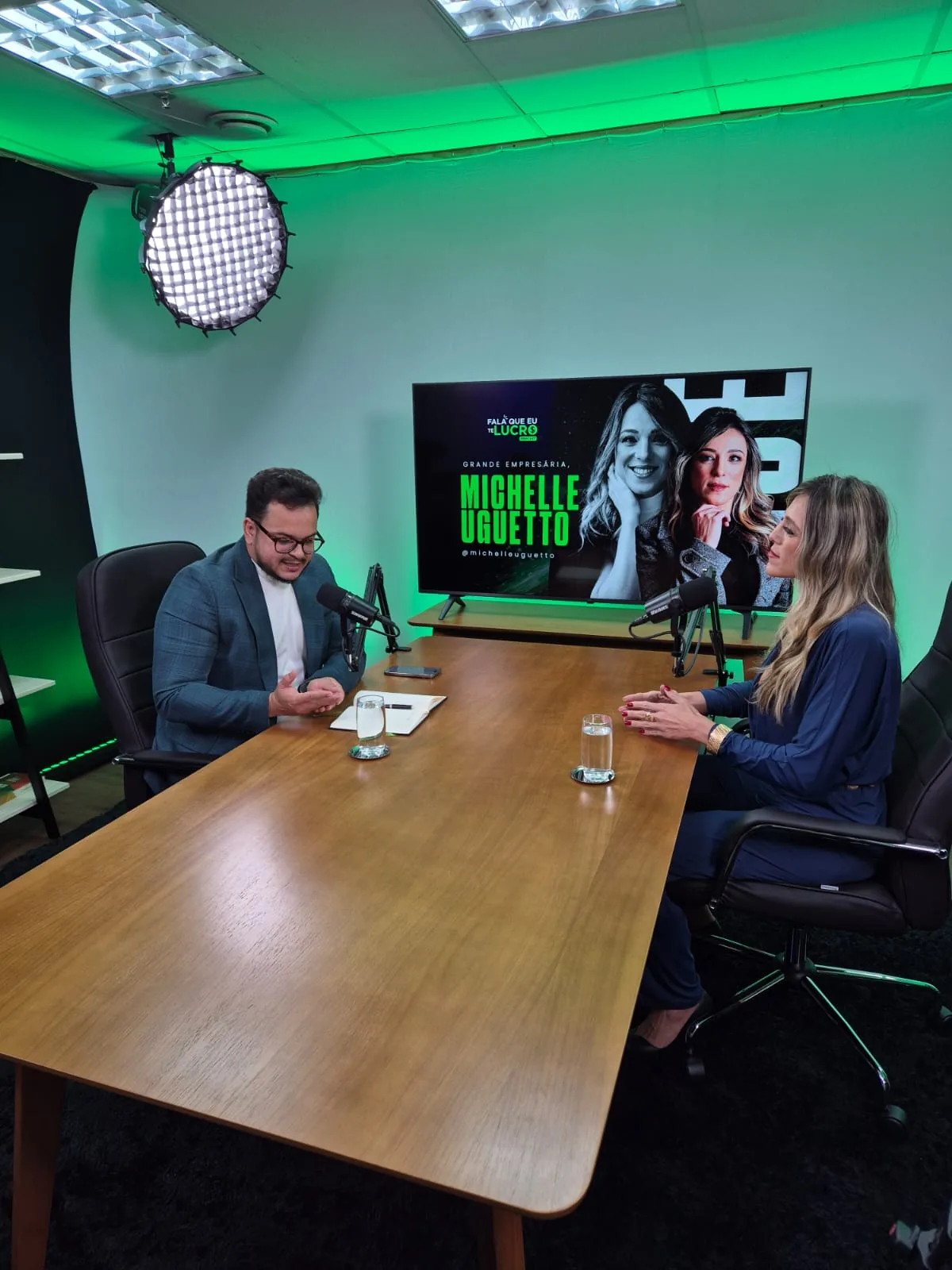 Convidados em volta da mesa de gravação em set azul
