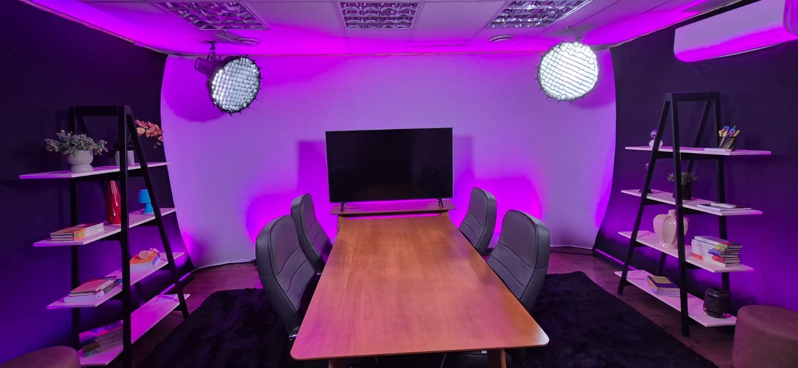 Estúdio da UniPod com iluminação roxa e mesa central