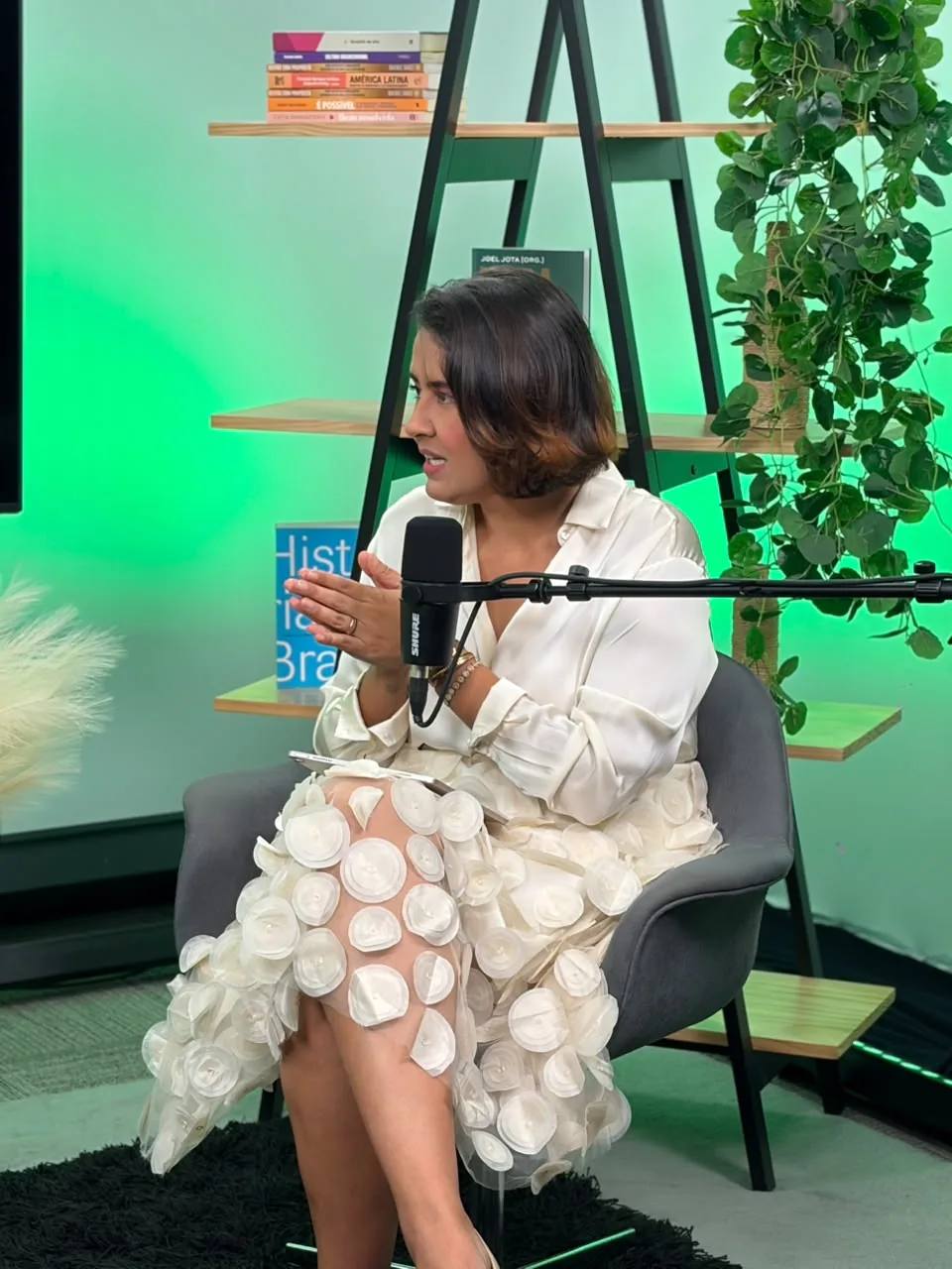 Apresentadora de close com microfone no fundo verde